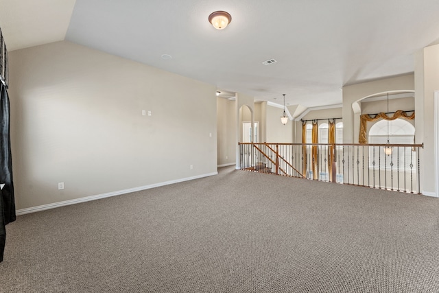 carpeted empty room with lofted ceiling, visible vents, and baseboards