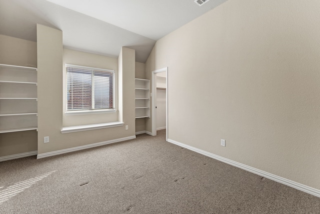 unfurnished bedroom featuring carpet, lofted ceiling, baseboards, and a spacious closet