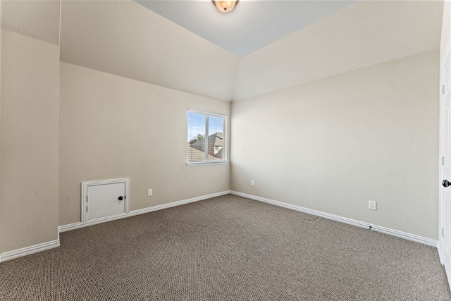 carpeted spare room with baseboards and vaulted ceiling