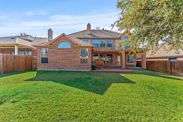 rear view of property with a patio, a fenced backyard, brick siding, a lawn, and a chimney