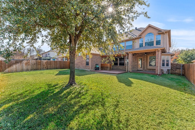 back of house with a patio, brick siding, a lawn, and a fenced backyard