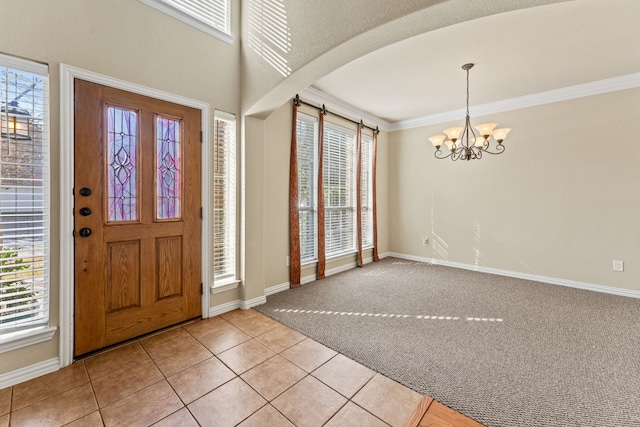 entryway featuring arched walkways, ornamental molding, light tile patterned floors, and light colored carpet