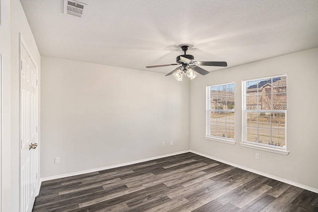 spare room with visible vents, dark wood finished floors, a textured ceiling, and baseboards