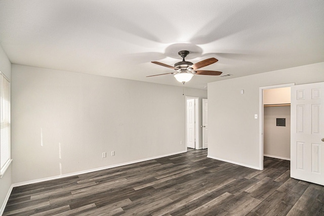 interior space featuring baseboards, visible vents, dark wood-style floors, ceiling fan, and a spacious closet