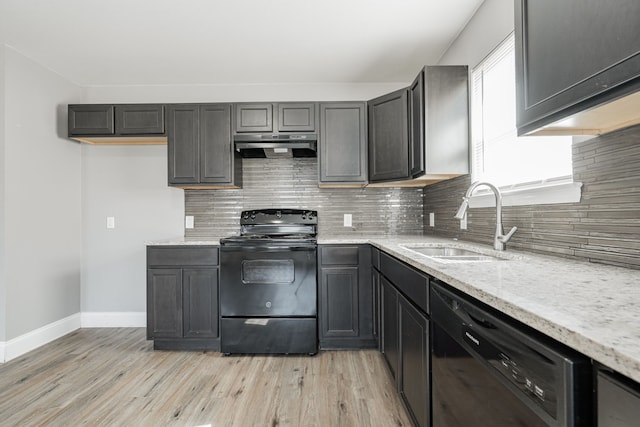 kitchen with backsplash, a sink, light stone countertops, under cabinet range hood, and black appliances