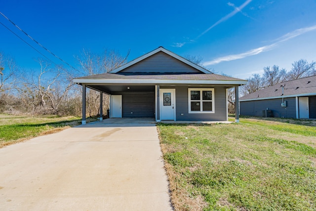 view of front of property with central air condition unit, an attached carport, a front lawn, and concrete driveway