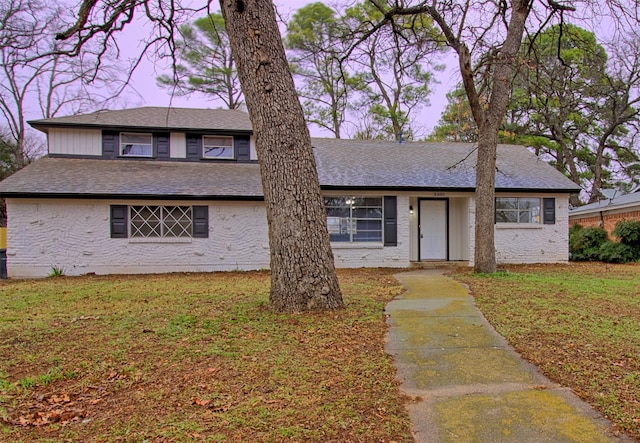 view of front of property with a front lawn and a shingled roof