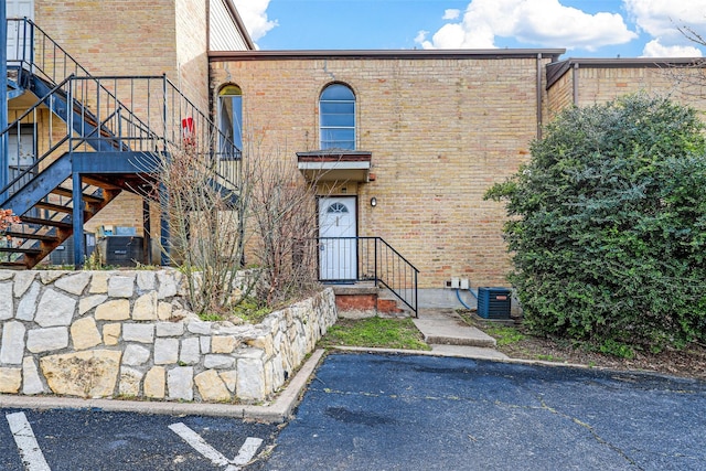 exterior space featuring uncovered parking, cooling unit, and brick siding