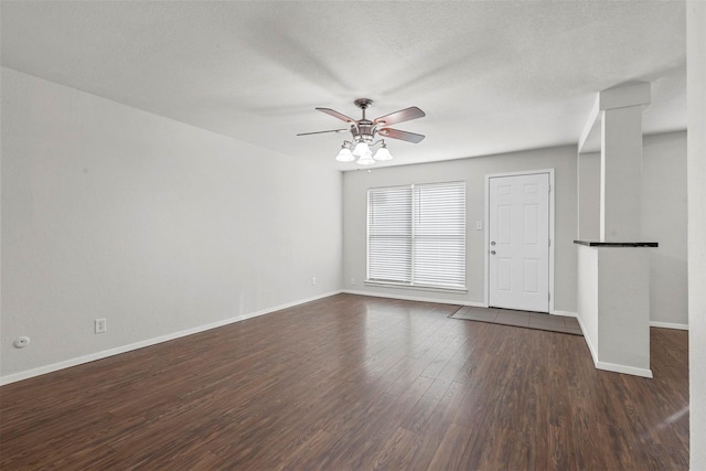 unfurnished room with ceiling fan, a textured ceiling, dark wood finished floors, and baseboards