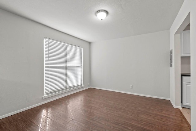 spare room featuring a textured ceiling, baseboards, and wood finished floors