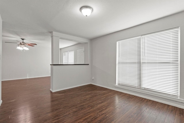 empty room featuring a textured ceiling, wood-type flooring, a ceiling fan, and baseboards