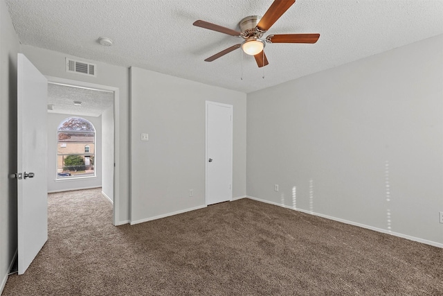 carpeted empty room with a textured ceiling, ceiling fan, visible vents, and baseboards