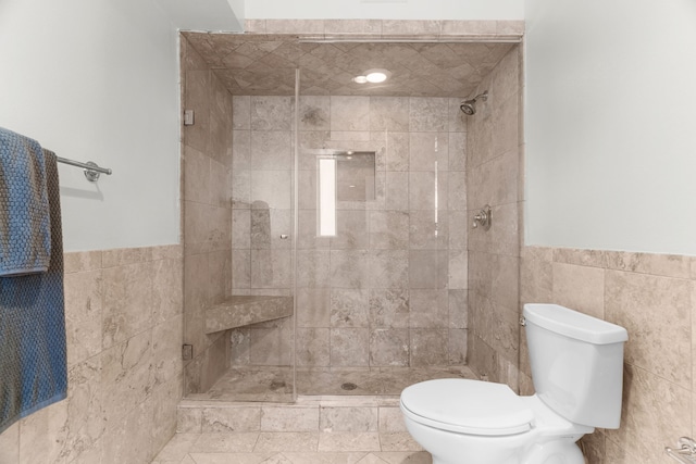 full bath with a stall shower, wainscoting, tile walls, and toilet