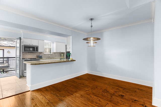 kitchen featuring decorative light fixtures, stainless steel appliances, tasteful backsplash, white cabinetry, and a peninsula