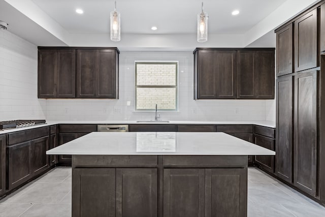 kitchen with a kitchen island, light countertops, a sink, and decorative light fixtures