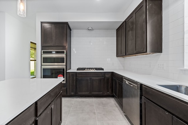 kitchen with light tile patterned floors, tasteful backsplash, appliances with stainless steel finishes, hanging light fixtures, and light countertops
