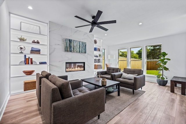 living area with a fireplace, recessed lighting, light wood-style floors, a ceiling fan, and baseboards