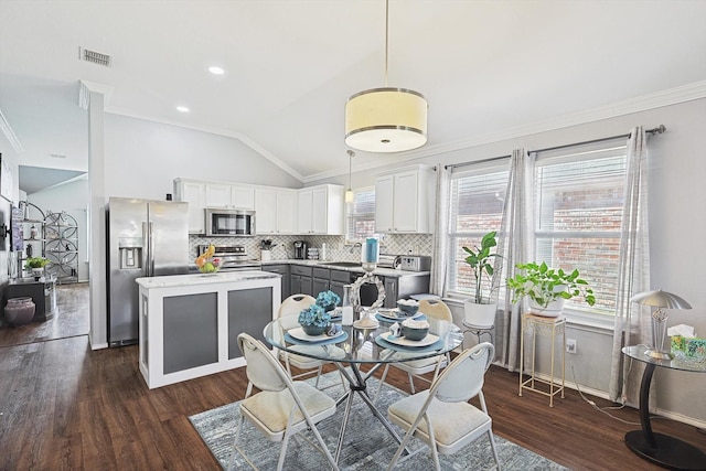 dining area featuring vaulted ceiling, visible vents, dark wood finished floors, and ornamental molding