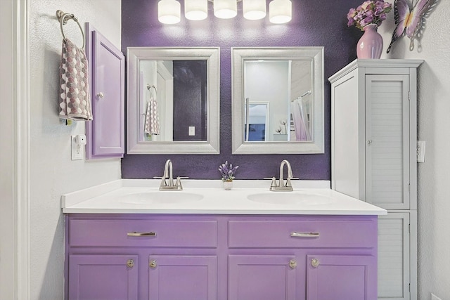 full bath featuring double vanity, a sink, and a textured wall