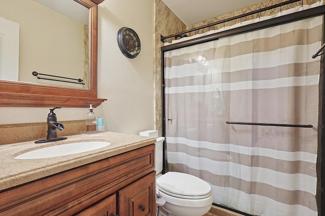 bathroom with toilet, a textured wall, a shower with shower curtain, and vanity