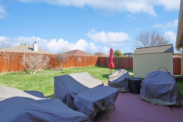 view of patio / terrace with an outbuilding, a storage unit, area for grilling, and a fenced backyard