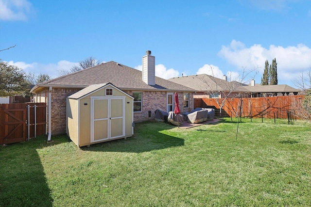 rear view of house featuring brick siding, a fenced backyard, a yard, and a shed