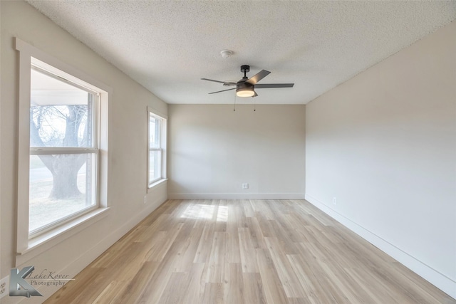 empty room featuring light wood-type flooring, ceiling fan, baseboards, and a textured ceiling