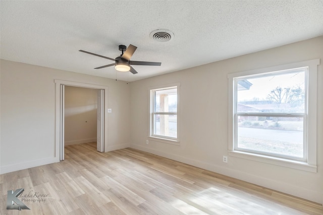 empty room with light wood-style flooring, visible vents, and baseboards