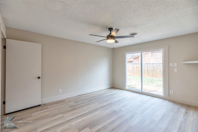 empty room featuring a textured ceiling, a ceiling fan, baseboards, visible vents, and light wood-style floors