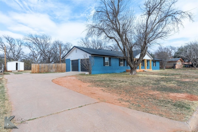 ranch-style house with a garage, a storage shed, driveway, an outbuilding, and brick siding