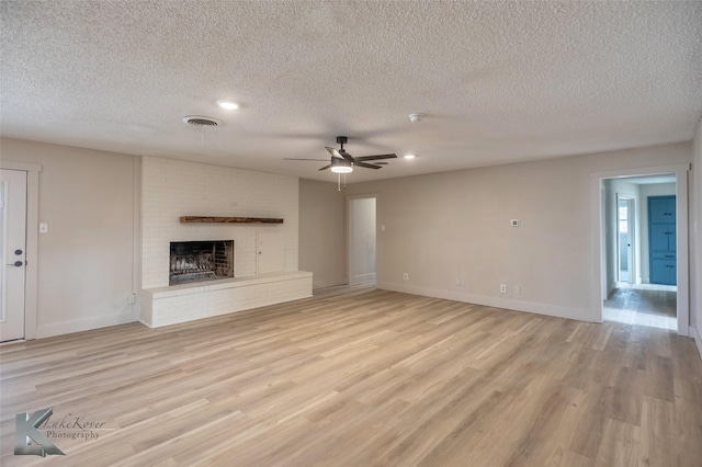 unfurnished living room with baseboards, visible vents, a fireplace, and light wood finished floors