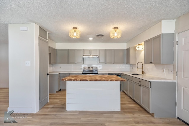 kitchen with a kitchen island, wood counters, gray cabinets, stainless steel range with electric cooktop, and a sink