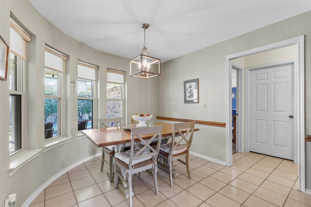 dining area with light tile patterned floors, a notable chandelier, and baseboards