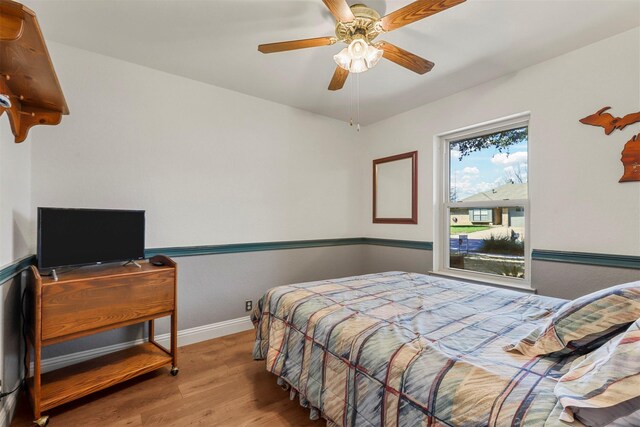 bedroom featuring wood finished floors, baseboards, and ceiling fan