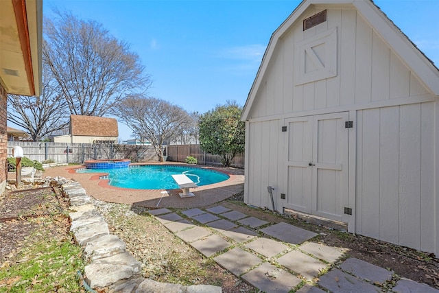 view of swimming pool with a fenced in pool, a storage shed, a fenced backyard, an outbuilding, and a diving board