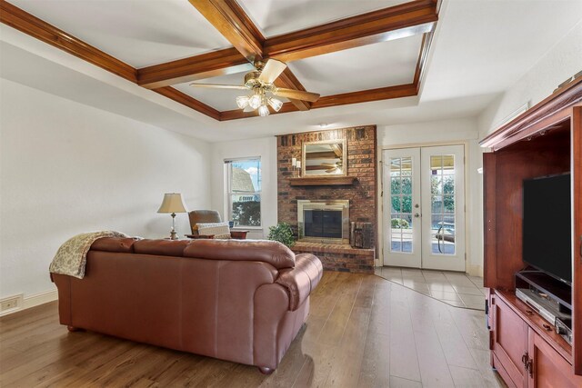 living area with a healthy amount of sunlight, coffered ceiling, french doors, and hardwood / wood-style floors