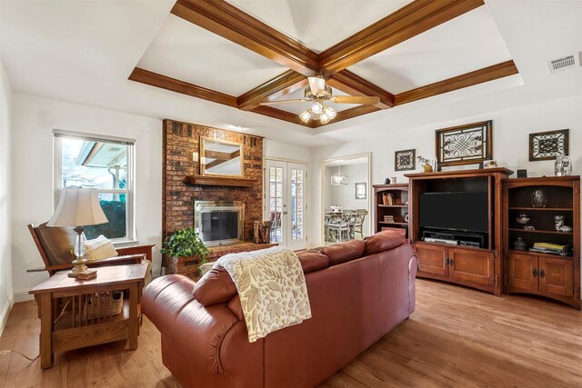 living area with a wealth of natural light, visible vents, light wood finished floors, and coffered ceiling