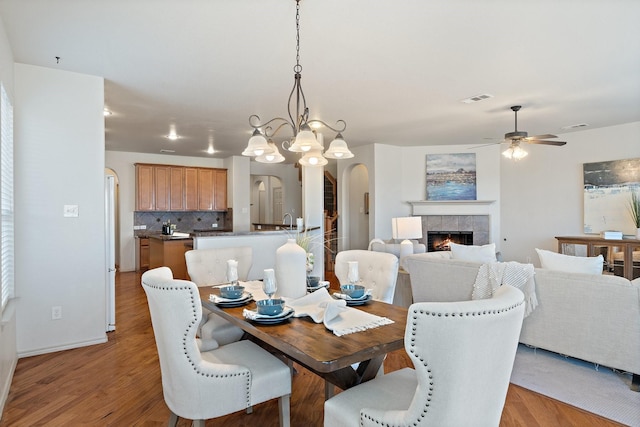 dining area featuring light wood-style floors, a fireplace, visible vents, and arched walkways