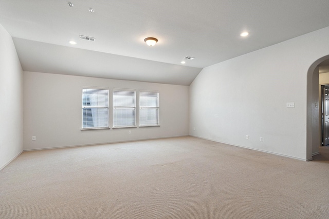 empty room with arched walkways, lofted ceiling, recessed lighting, light colored carpet, and visible vents