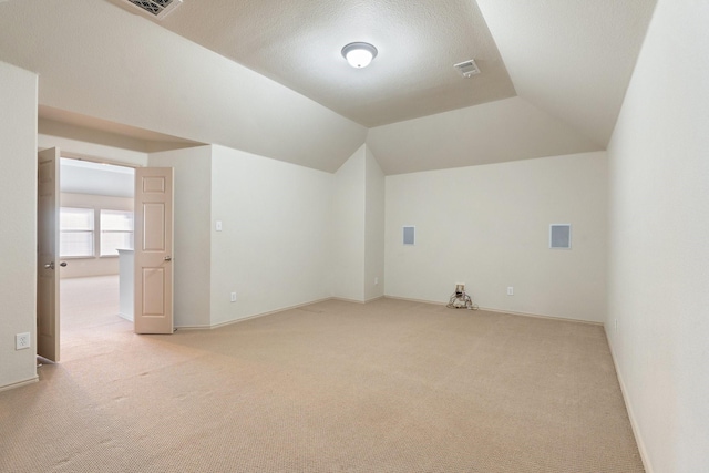 bonus room with lofted ceiling, baseboards, visible vents, and light colored carpet