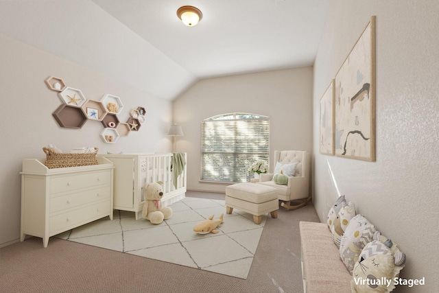 bedroom with lofted ceiling, a crib, and light colored carpet