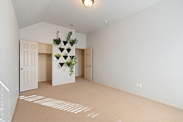 unfurnished bedroom featuring carpet, visible vents, vaulted ceiling, and baseboards