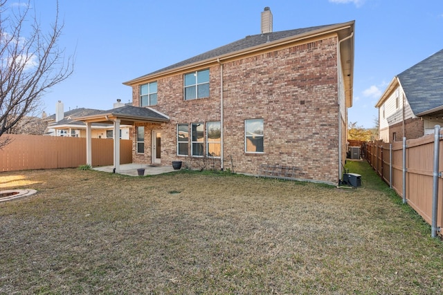 back of property with a chimney, brick siding, a patio, and a fenced backyard