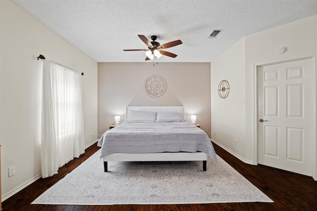 bedroom with dark wood-type flooring, visible vents, a textured ceiling, and a ceiling fan