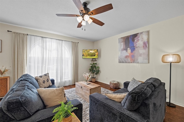 living room with dark wood finished floors, a textured ceiling, baseboards, and ceiling fan