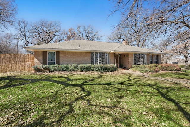 ranch-style house featuring brick siding, a front lawn, a chimney, and fence