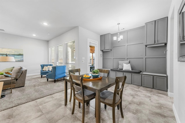 dining room with baseboards, visible vents, a chandelier, and a decorative wall