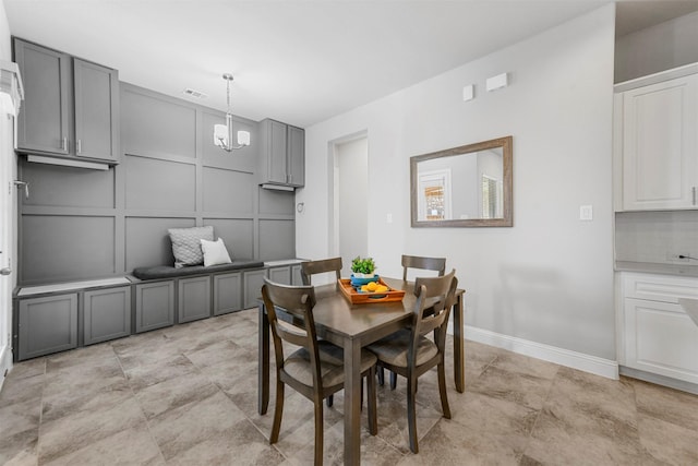 dining space featuring baseboards, visible vents, a decorative wall, and a chandelier