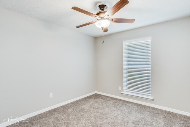 empty room with carpet flooring, ceiling fan, and baseboards