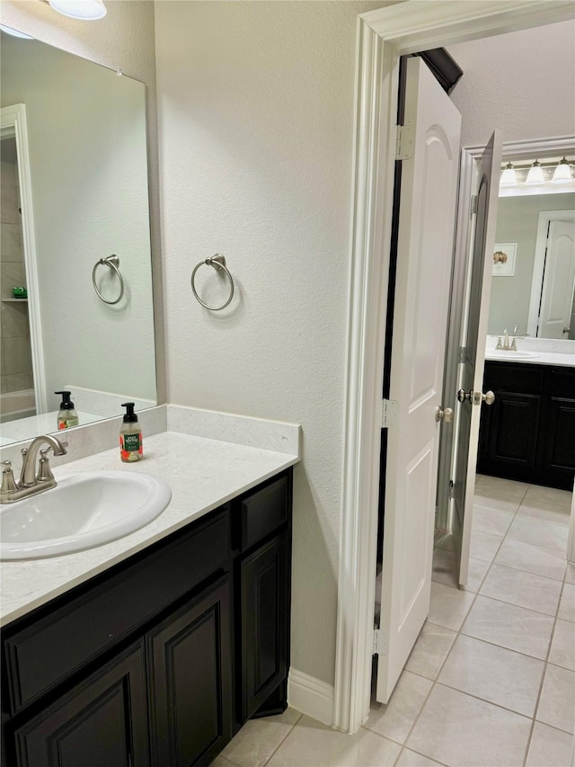 full bathroom featuring tile patterned flooring, two vanities, and a sink